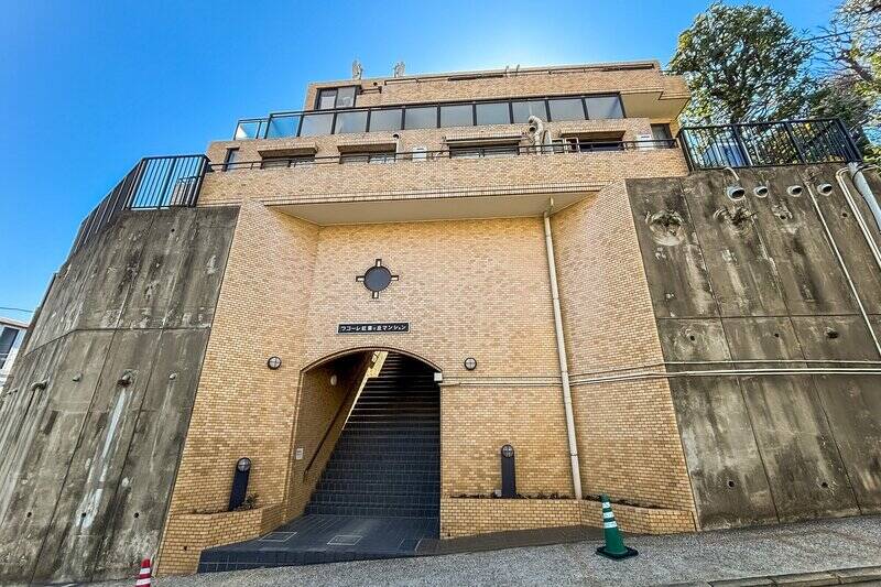 1986年竣工、総戸数21戸。城壁のようなタイル貼りのアーチから階段を上ってエントランスへ。マンションにはエレベーターがないため、住戸のある3階までも階段を使います。