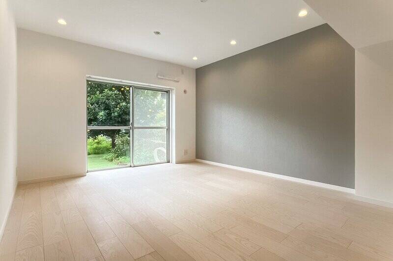 壁一面にはグレーのアクセントクロスが施されています。南側の掃き出し窓から光が入り、LDK全体が明るい印象です。