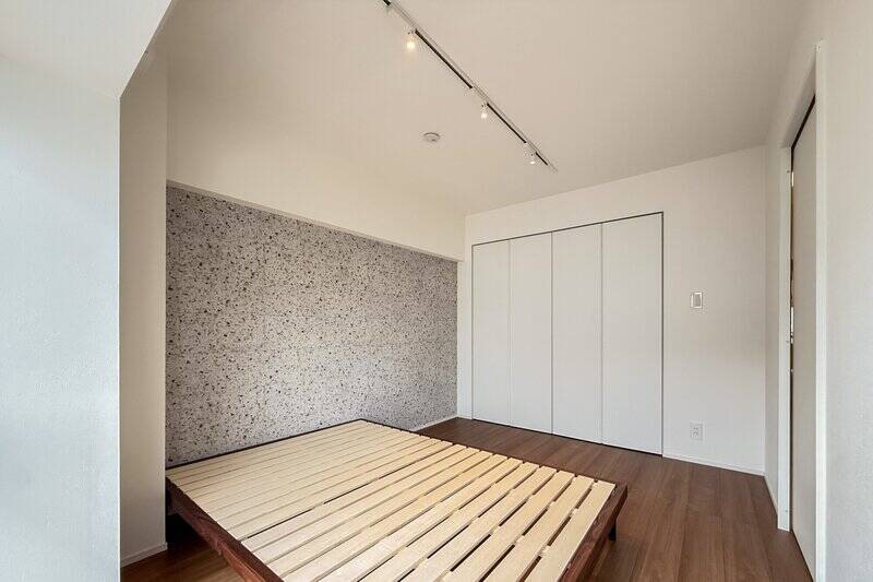 石調のアクセントウォールが空間のポイントに。折れ戸2枚分の収納付き。