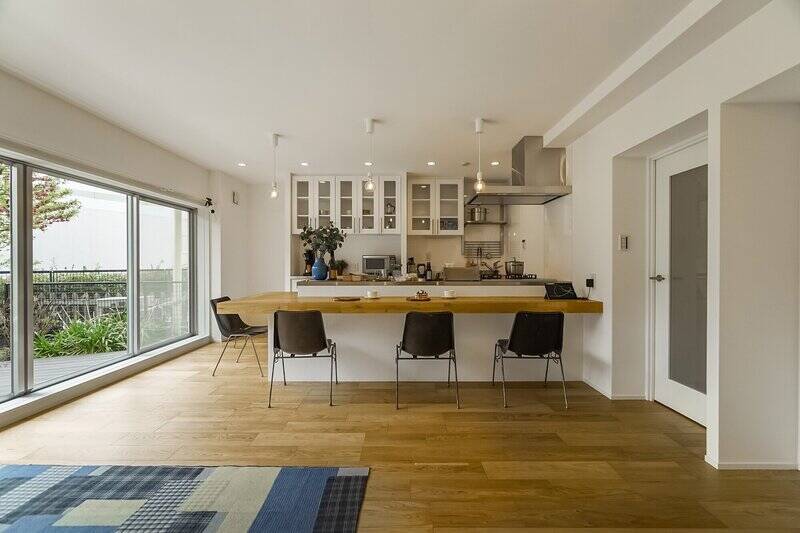 壁や天井はホワイトで統一され、足元はオーク材のフローリングで仕上げられています。ダイニングテーブルを兼ねた大きなカウンターのあるキッチンが、空間の主役です。