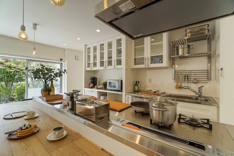 キッチンは、シンク側とコンロ（3口）側に分かれたセパレートタイプのものが採用されています。壁一面にカップボードが設置されており、収納力たっぷり。家電やゴミ箱などもすっきり格納できそうですよ。