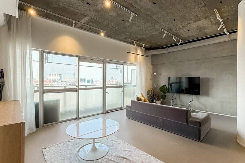 キッチン側からバルコニーに向いたカット。5枚並ぶ窓は開放感◎ テレビ側の壁面はモルタル塗装で仕上げています。