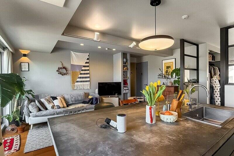 再びLDKへ。モルタル天板の中央にもポップアップ式のコンセントが取り付けられています。またライティングレールが梁横に付いているため、お好きな位置に照明の取り付けが可能。現在テレビを置かれている場所の横には細長い可動棚も。