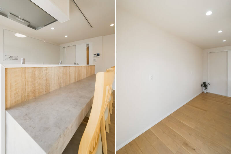 <b>左・</b>カウンターはモルタル調・木目調で仕上げられており、天井にはダクトレールが設置されています。お好みの照明でさらにムードを高めましょう。/<b>右・</b>キッチンの背後には余裕たっぷりのスペースが確保されています。ちょっと見づらいですが、コンセントが複数箇所あり、冷蔵庫を置く場所が限定されていないのもありがたいですね。