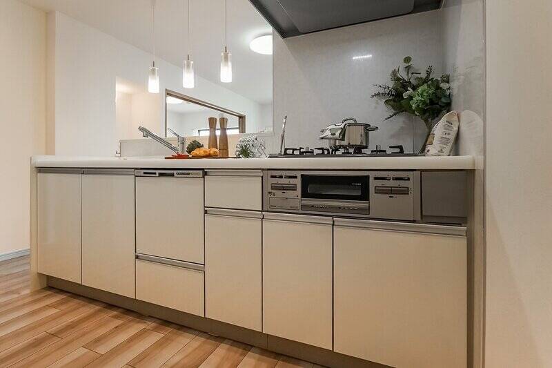 キッチンは3口コンロと食洗機付き。ワイドサイズでお料理が捗りそう。背面には、冷蔵庫とキッチンボードを置くスペースがありますよ。