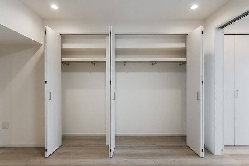 壁面に並んだ折れ戸を開けると、収納スペースが。枕棚のほか、5つのハンガーパイプが配されています。衣服の種類ごとに、仕分けて収納できますね。