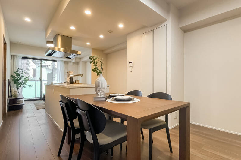 奥行きのあるLDK。アイランドキッチンを中心に、白を基調とした空間が広がっています。