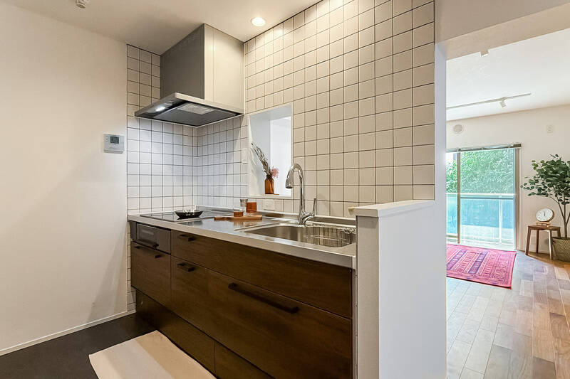 白タイル＋グレー目字の壁面が可愛い。真ん中にはリビングダイニング（LD）の様子が伺える開口が設けられています。