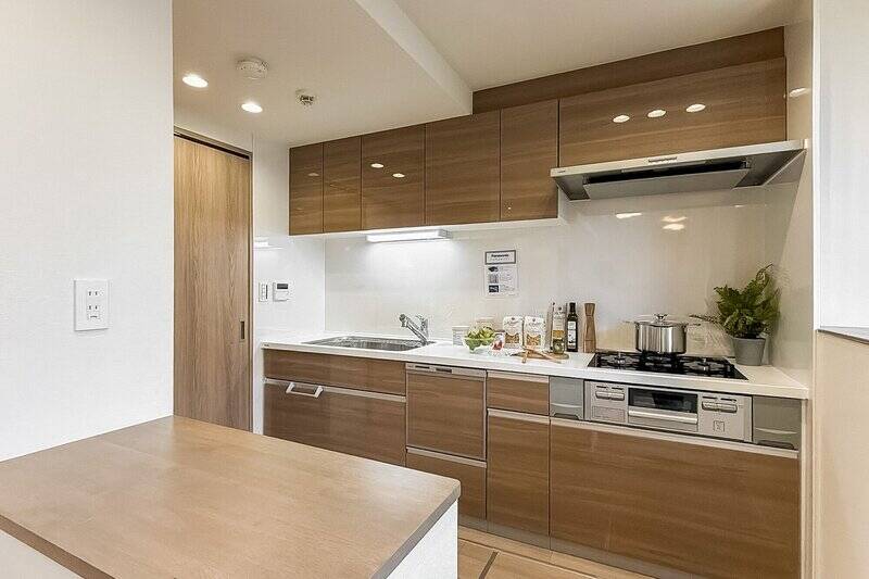 本体はワイドタイプで、3口コンロ・食洗機付き。ダイニング側にはカウンターがあり、出来上がった料理の配膳もしやすそう！ カウンター横には冷蔵庫置き場があり生活感が出づらい工夫が。左手の扉の中はパントリーです。