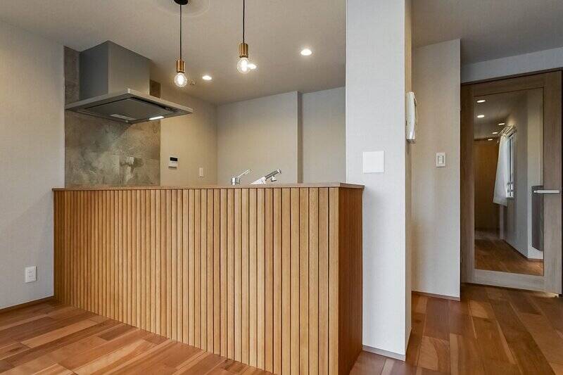 ウッドリブパネルが印象的なキッチン。腰壁のおかげでキッチンの内部は見えづらく、生活感を抑えられます。