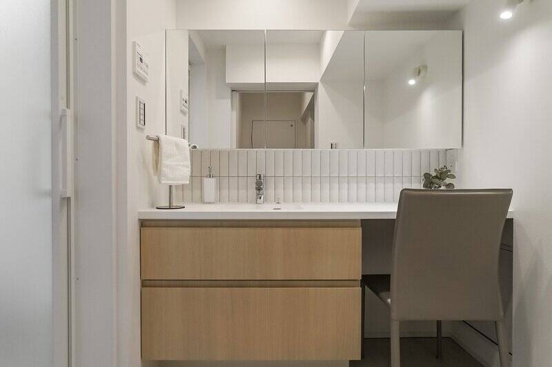 洗面化粧台はワイドなつくりで、座って支度ができるスペースも確保。白いタイル貼りがさりげないアクセントとなり、空間に表情を添えています。