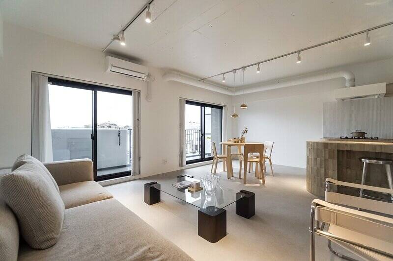 まずは約20.8帖のLDKにやってきました。躯体現し+白塗装仕上げの天井が今っぽい雰囲気! 壁は塗装風のクロス、足元はごく淡いグレージュのフロアタイルが敷き詰められています。