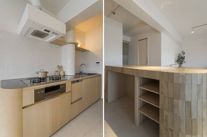 <b>左・</b>ちょっと珍しい、曲面デザインのキッチン。壁面には白の細いタイルがあしらわれています。/<b>右・</b>カウンター側には、可動棚やゴミ箱用のスペースが。調理の作業台としても、ちょっとしたバーカウンターとしても、大活躍してくれそうですね。ちなみに、奥に見えているのは水まわりの引き戸です。