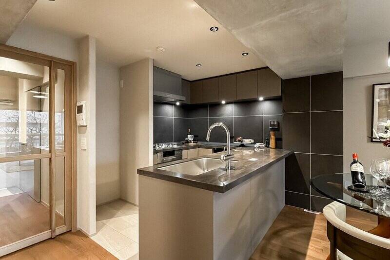 こちらの住まいの主役とも言える、コの字型の大型キッチン。ダークブラウンのタイルがシックな印象です。