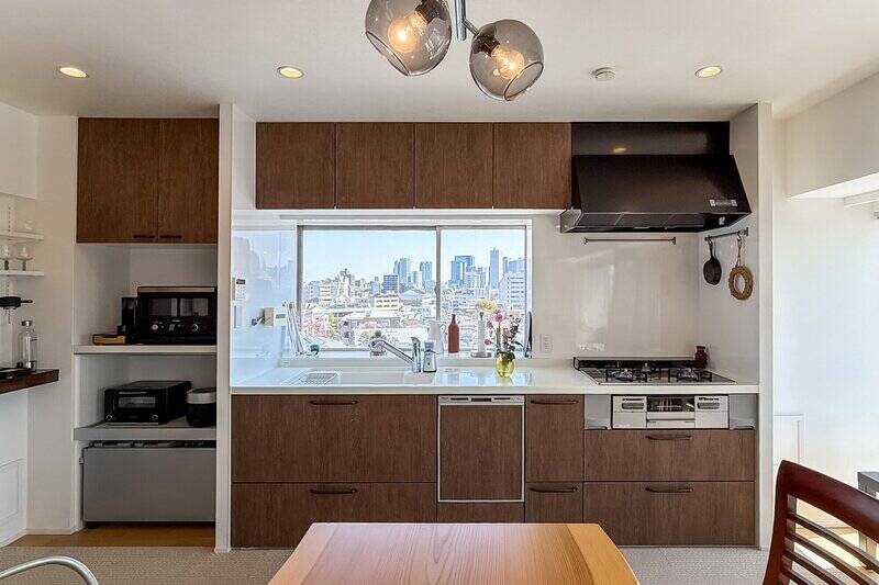 キッチンは3口コンロタイプで食洗機付き。調理中に視線を上げれば、窓の外には空と街並みが広がります。
