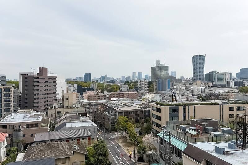 視線の先には「代々木公園」の緑、そして「代々木体育館」の屋根。さらに向こうには「青山」や「六本木」方面のビル群が見えています。