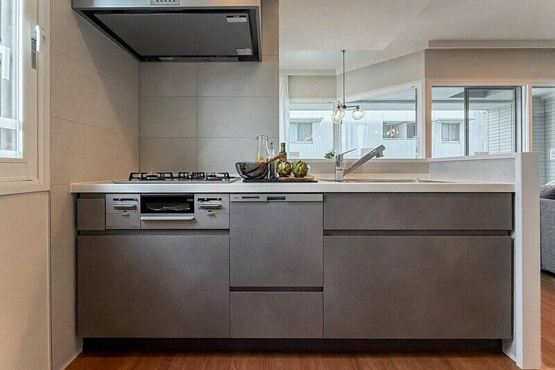 カウカモオリジナルのキッチンは、グレーを基調としたデザインに。うれしい食洗機・浄水器付きです。コンロ側の壁面はタイル貼り。大判タイルのため目地が少なく、お手入れしやすいところがGOODです。