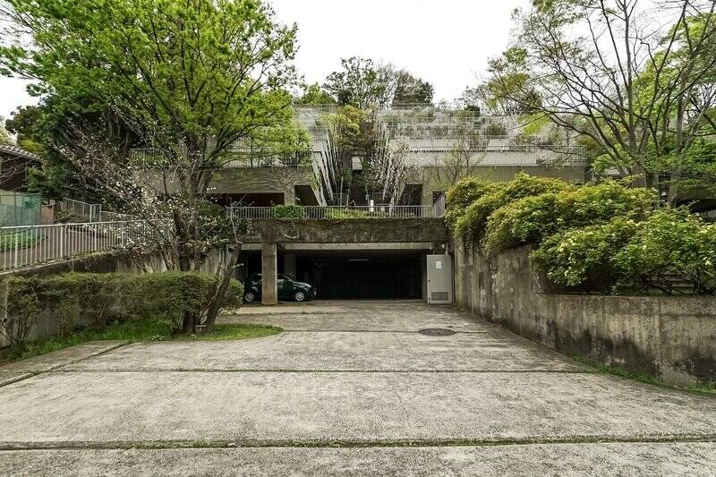 東急東横線「大倉山」駅から、起伏のある道を歩くこと17分。その先に現れるのは、<b>“斜面の魔術師”</b> と称される建築家「井出共治」氏が手がけた雛壇形状のマンション。緑に寄り添うように建つその姿は、この地形だからこそ生まれたもの。1987年竣工、新耐震基準適合の総戸数28戸です。