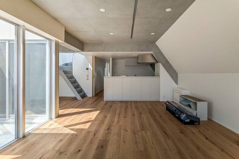 こちらは、約21帖のLDK。コンクリートの天井、白い壁面、フローリングの木目、それぞれがバランスよく調和する洗練された内装です。(2025年3月撮影。以降、住戸写真は同日撮影。)