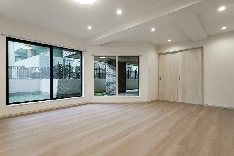 約17帖のLDK。北東・南東向きに窓が並んでいます。洋室Aにつながる引き戸を開けると……