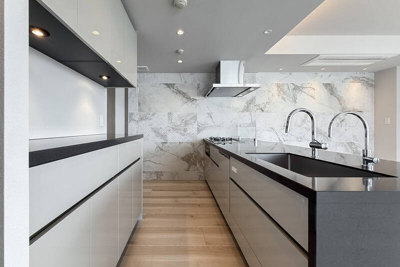 カップボードを含め、収納がたっぷり。壁面には特徴的な石調タイルが張られ、冷蔵庫はコンロ近くに置くことが想定されています。