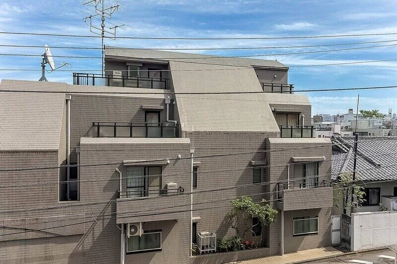 道路と敷地内の駐車場を挟んで4階建てのマンションが建っています。右手に視線を向けると、「三軒茶屋」駅前のランドマーク「キャロットタワー」が見えますよ。