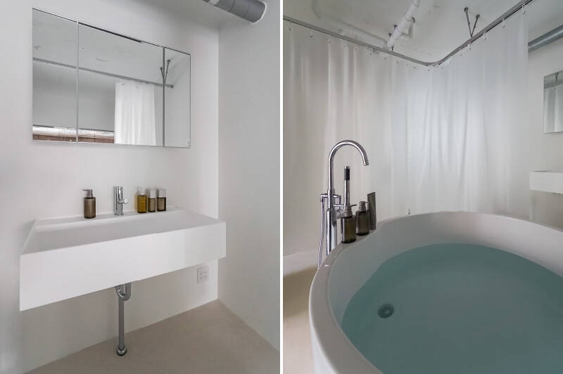 <b>左・</b>ミニマルなデザインの洗面化粧台。鏡の裏は奥行きの浅い収納です。／<b>右・</b>ユニットバスとは一線を画すおしゃれさの、円形バスタブ。必要に応じて、備え付けのシャワーカーテンで洗面＆トイレとバスタブをゆるく区切ることができます。とはいえ、それは水飛沫除けであって、目隠し用ではありません。LDKに面したガラス側にはカーテンレール無し！ 見せつけてゆくスタイルです。