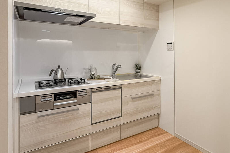 キッチンは3口コンロ、食洗機付きです。右手にはカップボードなどの収納を設置できそうなスペースが。キッチンの左手には冷蔵庫置き場があります。