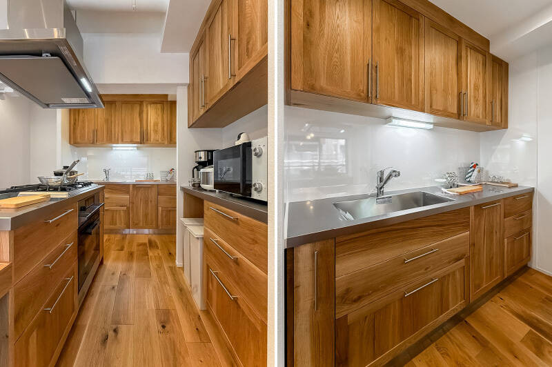 <b>左・</b>グリル付き3口コンロとオーブンを完備。背面には調理家電を置ける造作のカップボードも設置されています。／<b>右・</b>シンクは、コンロと分かれた造り。こちら側にもたっぷりと収納が用意されています。