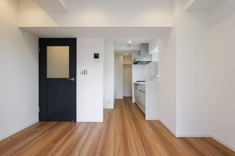 窓を背にしたカット。白を基調とした壁、温かみのある木目調のフローリングの中で、リビングドアのネイビーがアクセントになっている印象です。