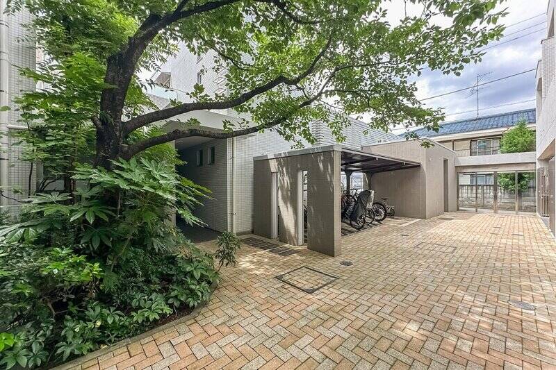 共用通路からサブエントランスを望む一枚。敷地内にも豊かな植栽が配され、ゆったりとした時間が流れるような景色が広がります。