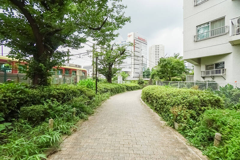 こちらは外に出て撮影したカットです。右に写っているのがご紹介の住戸で、左が都電荒川線。間には緑で彩られた遊歩道があり、マンションを囲むように神田川へと延びていきます。