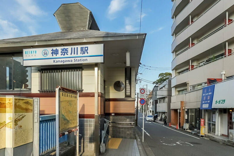 最寄りの京急本線「神奈川」駅。右手の建物が今回ご紹介するマンション。文字通り <b>“駅の目の前”</b> の物件です。（徒歩1分）