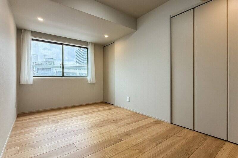 2箇所に収納が配された居室です。北向きの窓の先には広い駐車場があり、その分視界が開けています。将来的に何か建つ可能性は否定できませんので、事前にご留意くださいませ。