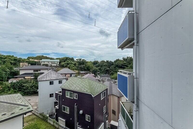 高台ならではの、周囲の緑や住宅街を見渡す景色。マンションが雁行した形状のため、右手には隣接する住戸の壁があります。