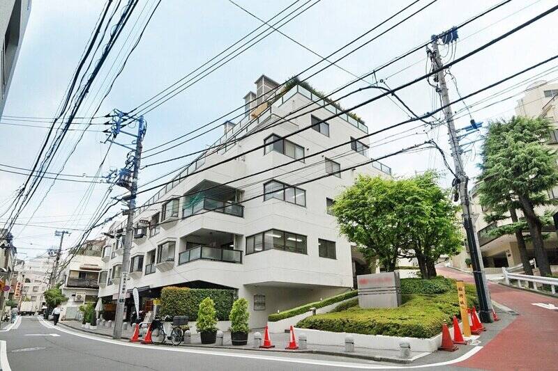 駅前の大通りから路地に入り、閑静な住宅街をしばらく歩くと……見えてきました！ 坂道にどっしりと佇む白い外観のマンションは、1973年築・総戸数118戸のビッグコミュニティです。1階部分にはテナントとしてクリーニング店や飲食店が入居しています。ちなみにお向かいにはコンビニエンスストアがあり、家庭の第二の冷蔵庫としての活躍が期待できますよ◎