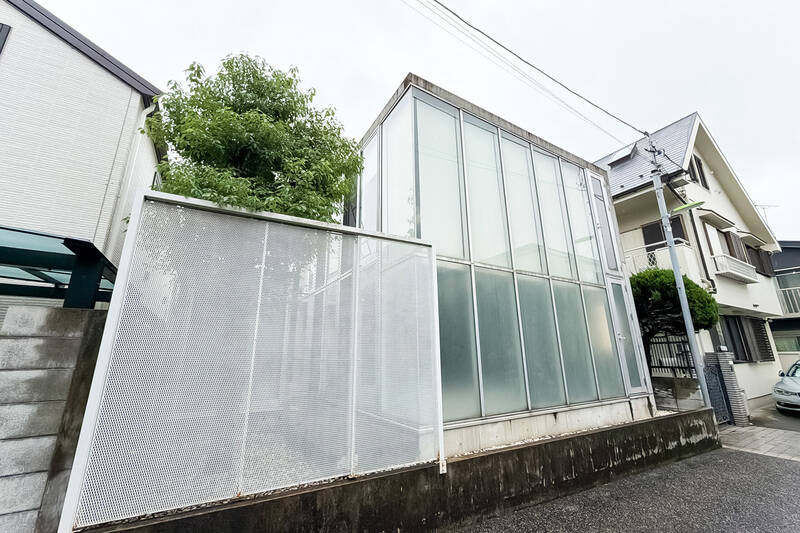 閑静な住宅街に佇む戸建て住宅。エントランスの裏側は、一面ガラス張りで、中の灯りが外まで届く、光る箱のような外観。すでに、ワクワクしてきました。