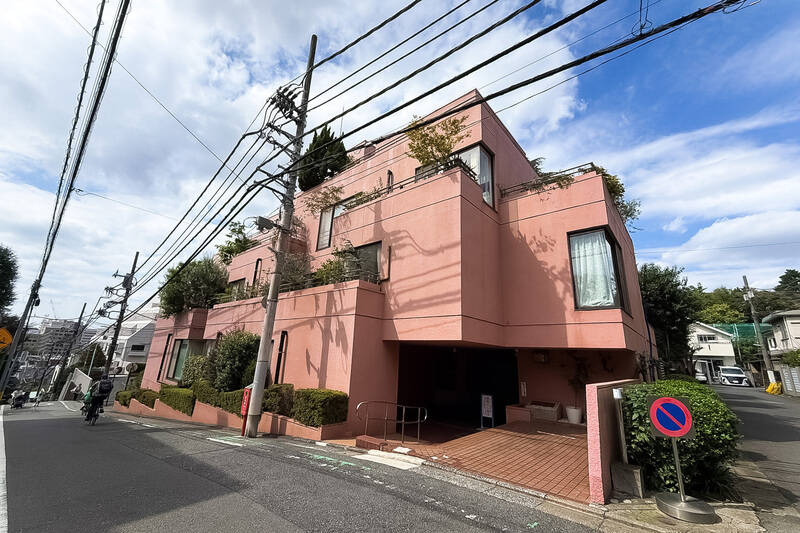 坂の上に建つ、ただならぬ佇まいの建物を発見……！ 目を引くのは、ハワイの “ピンクパレス” を思わせるような華やかな色合い。1979年竣工・総戸数17戸のマンションです。