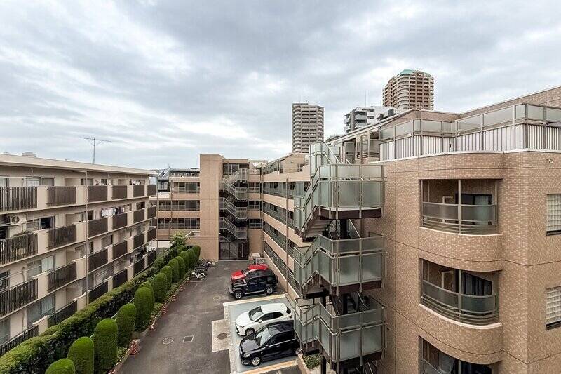 周辺には建物が建ち並び、眼下には隣地の駐車場が。一方、バルコニーの正面にはちょうど建物がなく、圧迫感は抑えられています。